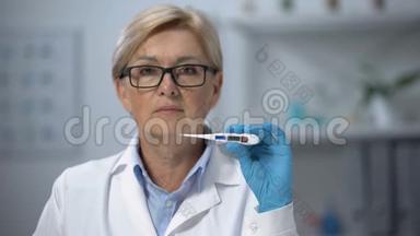 专业成熟的女医生在摄像机上显示电子体温计